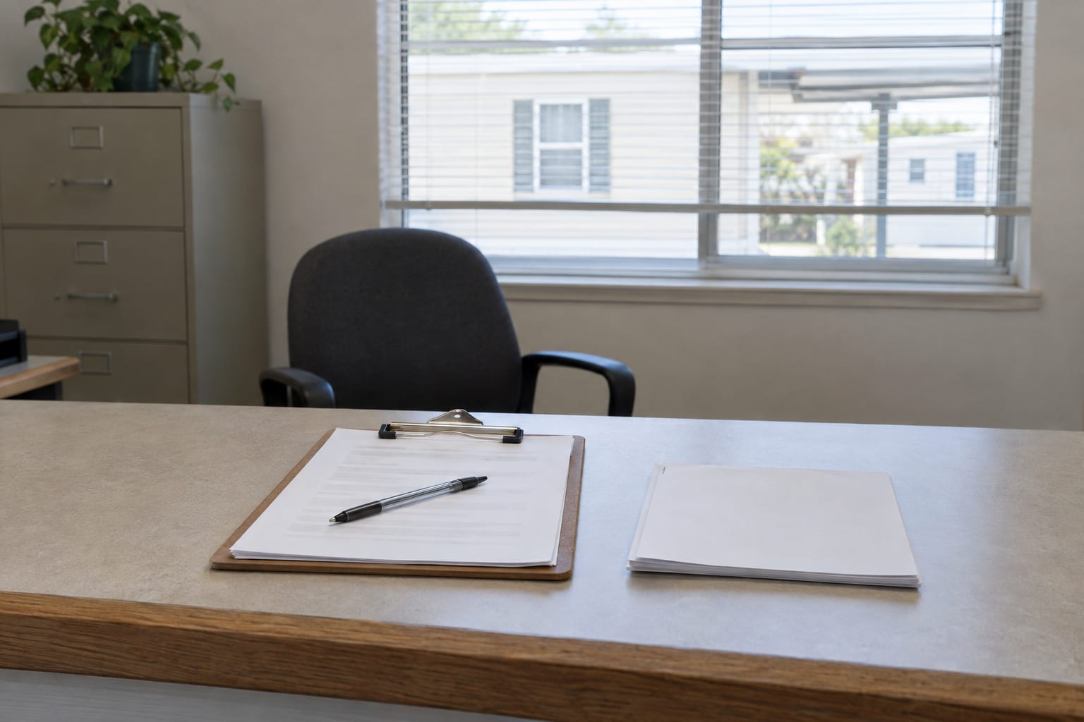 A clipboard holding a blank application, with a pen beside it, on the front counter of a community office