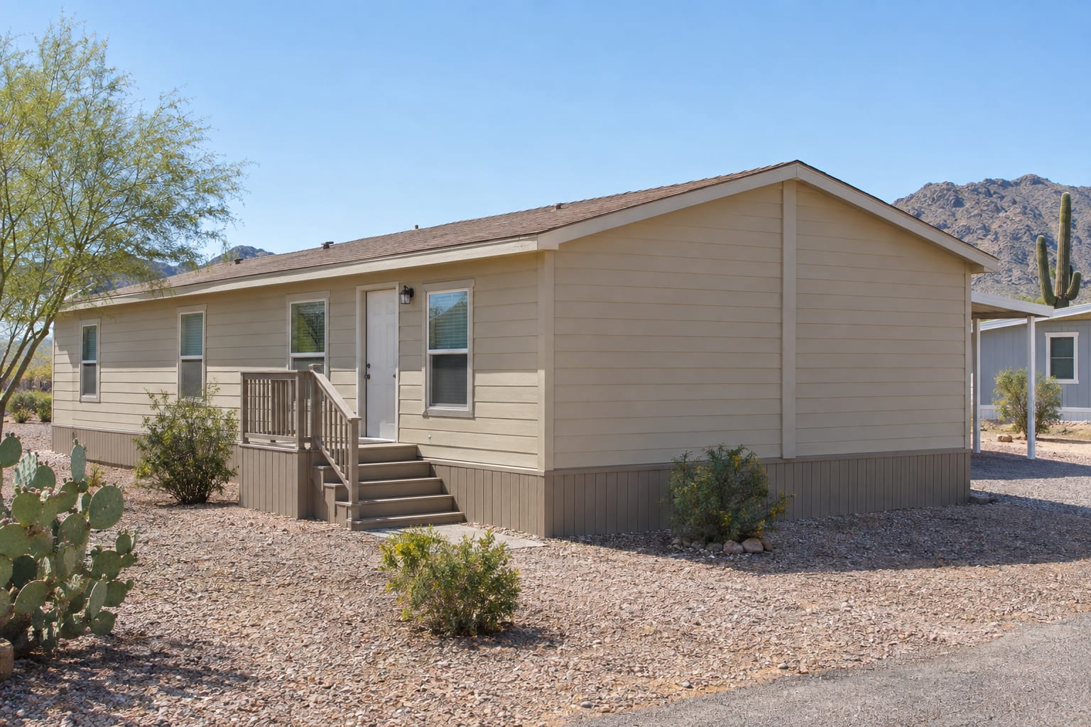 A double-wide manufactured home seen from its end wall, with a vertical trim board at the center where the two sections meet, on a gravel lot in Arizona.