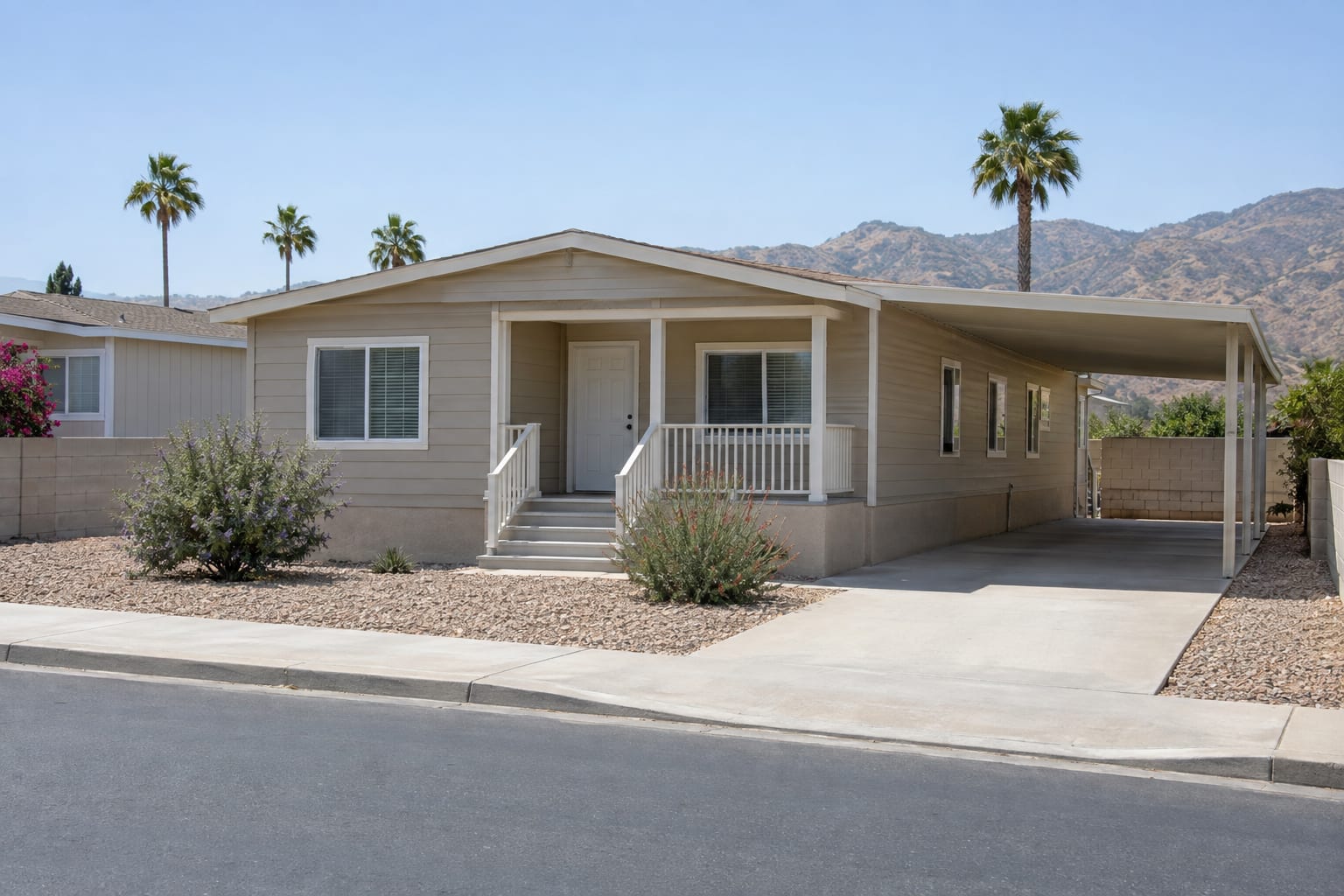 A manufactured home on its own lot with a concrete driveway and a carport, on a paved residential street