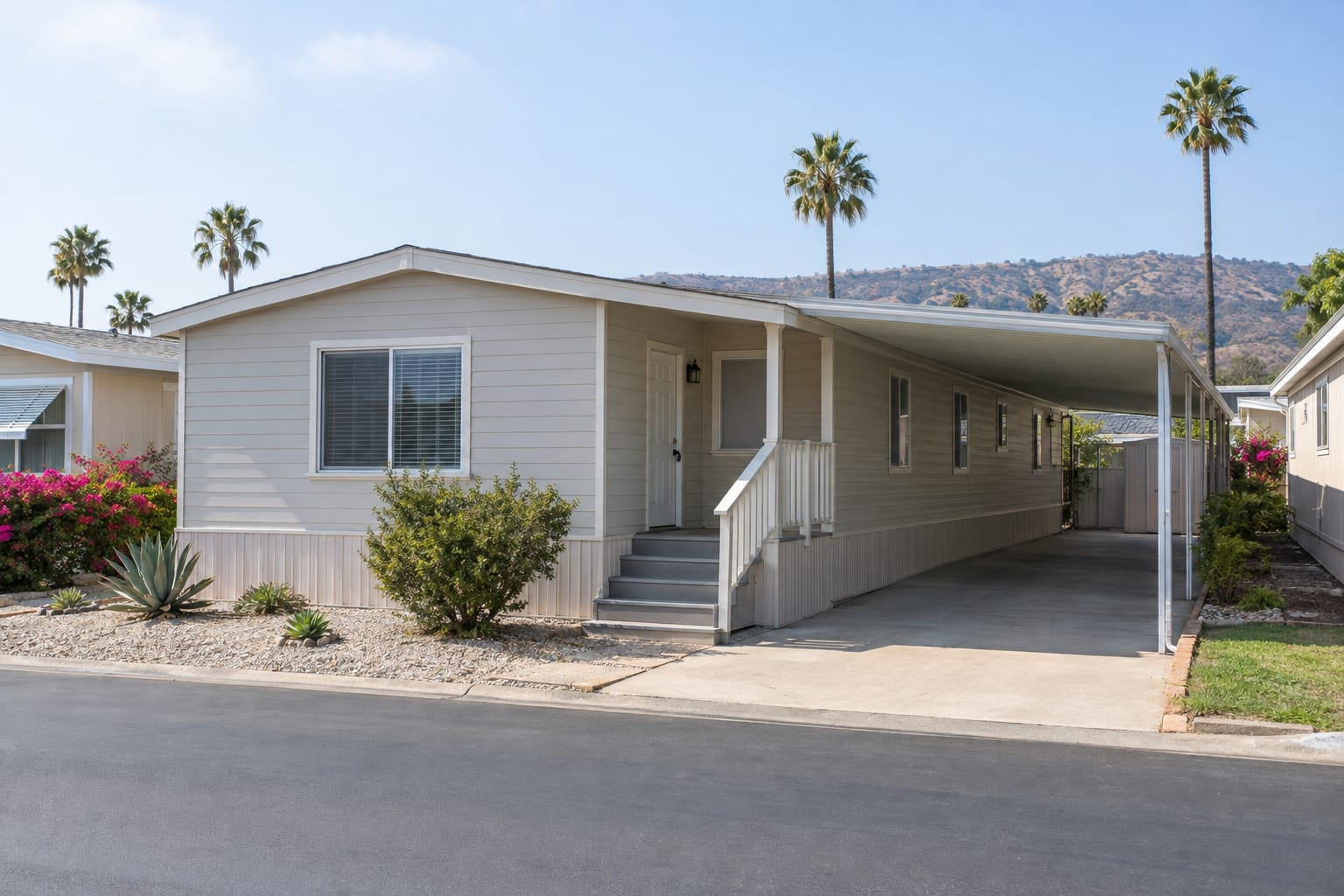 A double-wide manufactured home with a carport and a small covered porch on a quiet community street in Southern California.