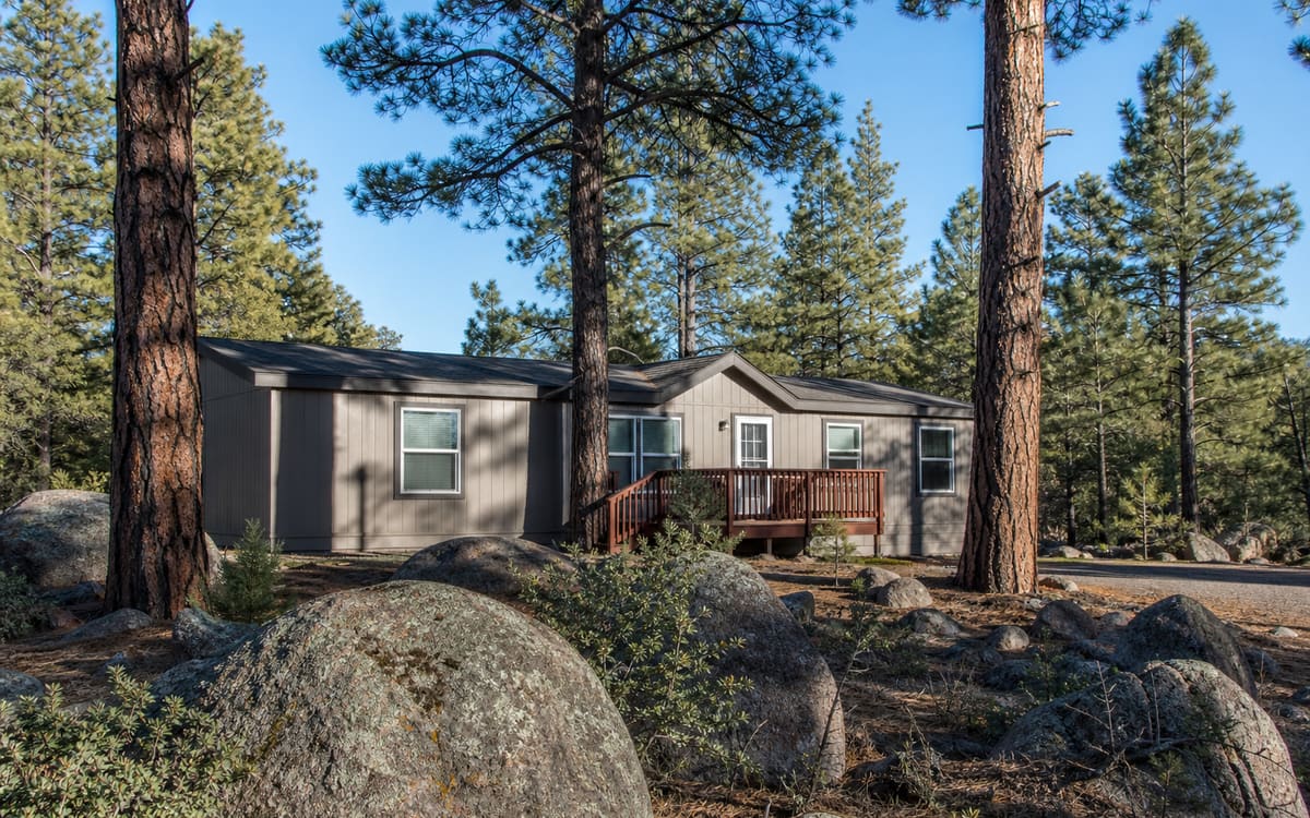 A manufactured home among ponderosa pines and granite boulders in central Arizona high country