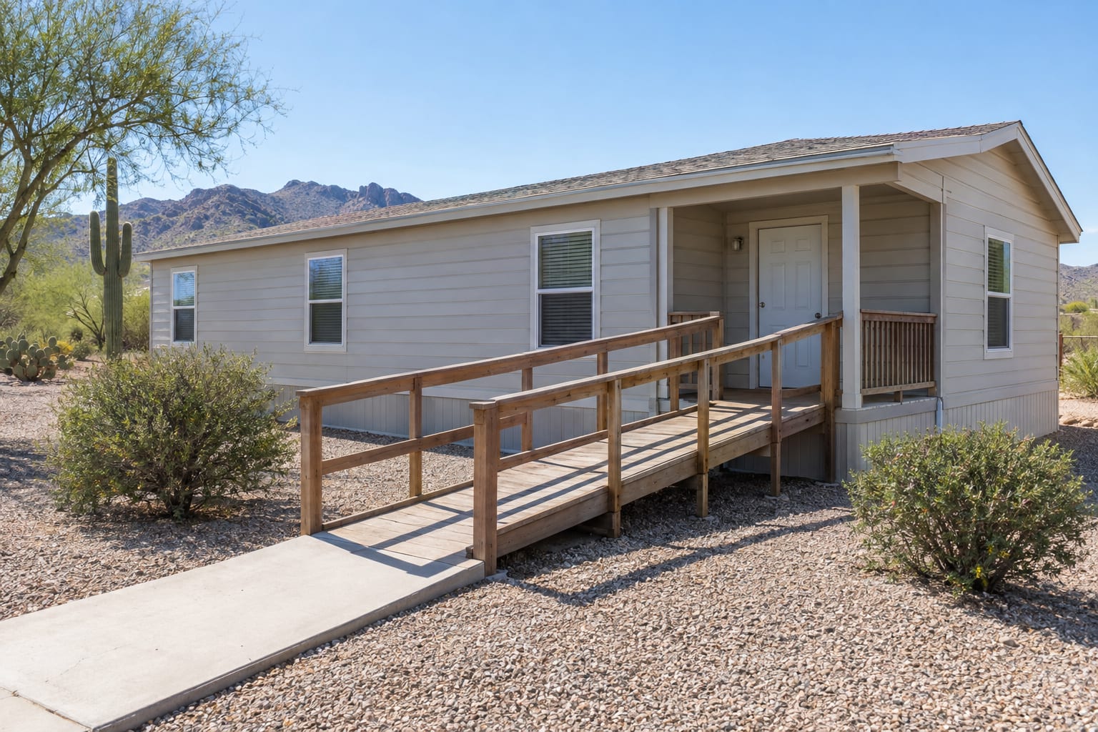 A wooden ramp with handrails leading up to the covered front porch of a manufactured home.